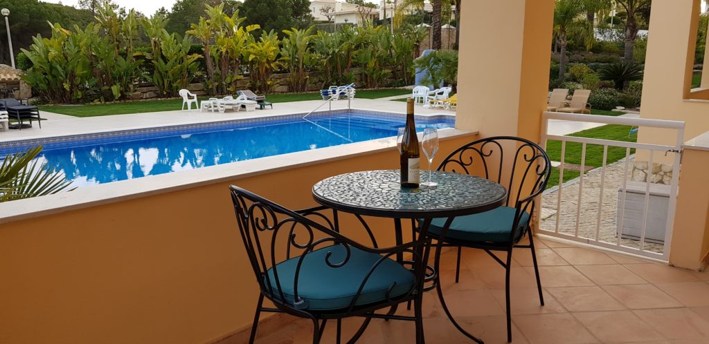 Bistro table & chairs on terrace leading from master bedroom overlooking pool & gardens
