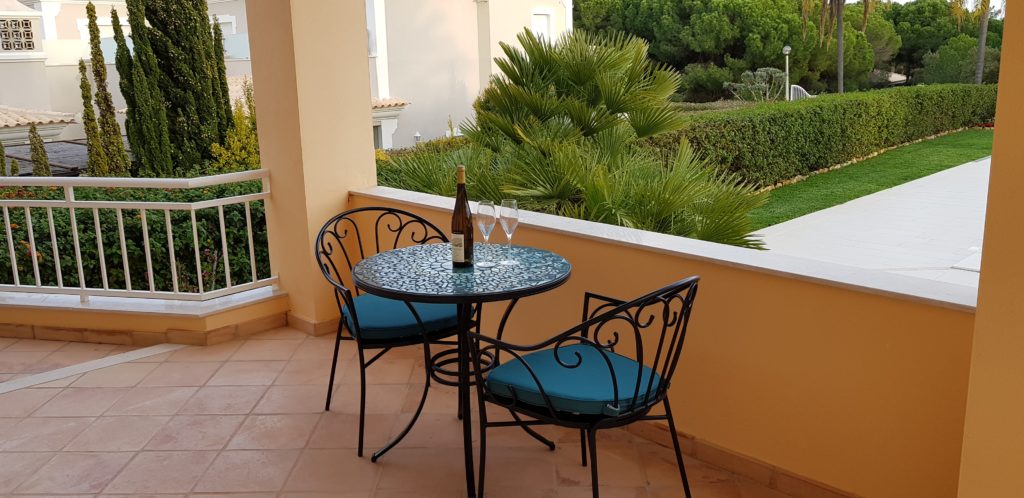 Bistro table & chairs on terrace leading from master bedroom overlooking pool & gardens